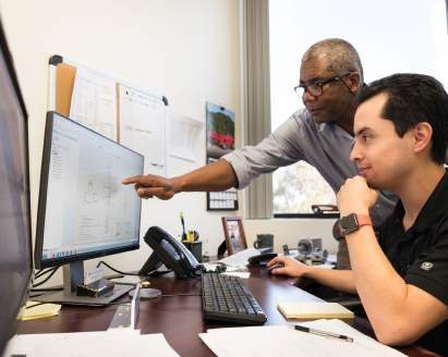 Two engineers looking at a desktop monitor